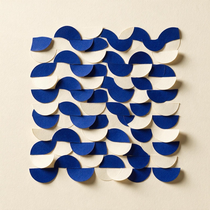 A repeating wave pattern of blue and white paper half circles